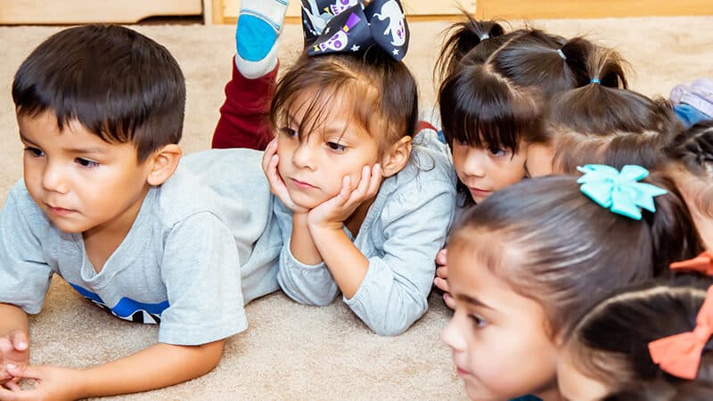 5 children gather in a half circle listening