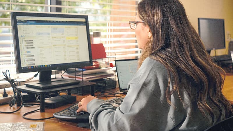 A woman sits at a desk looking at a computer screen